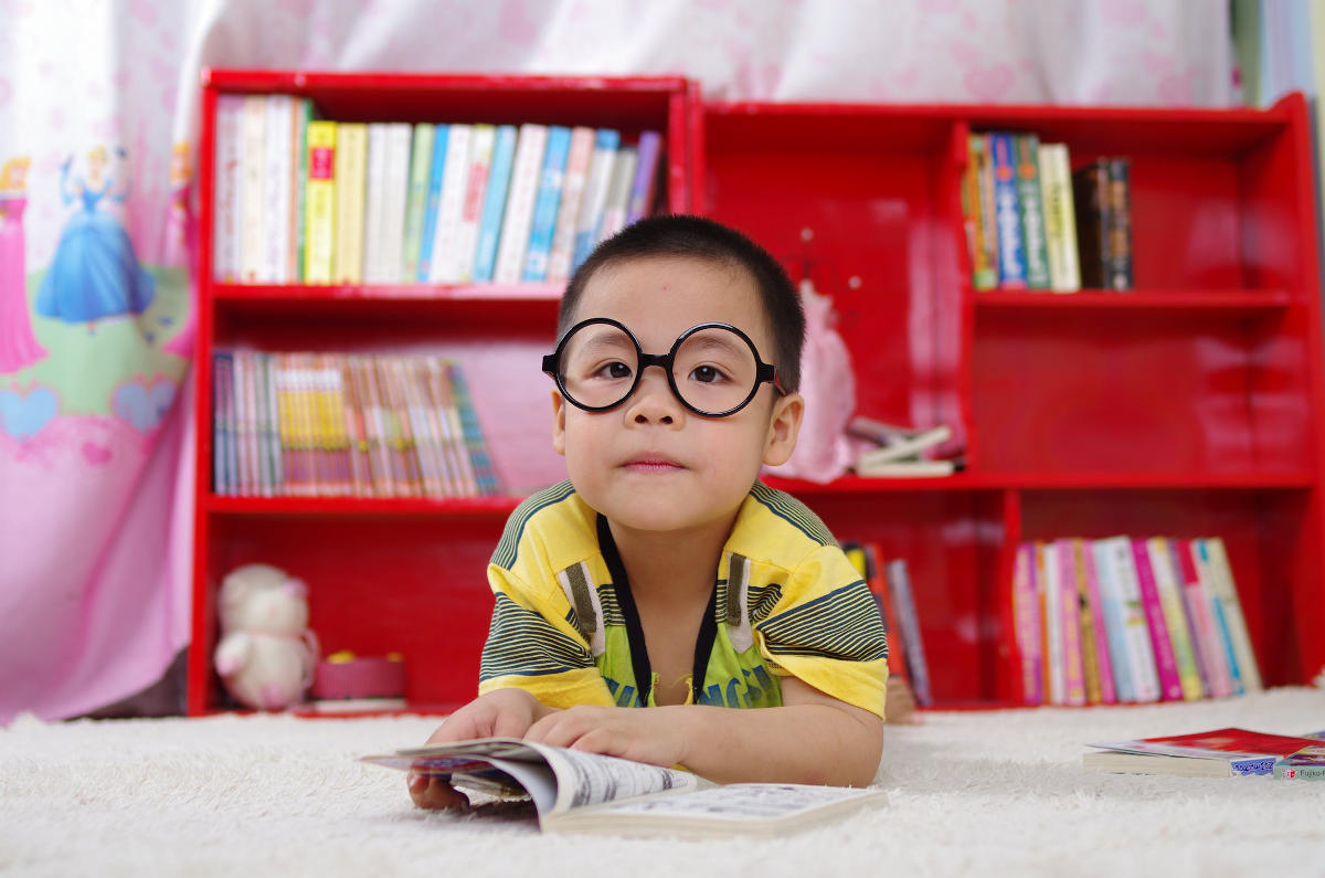 A boy with glasses over a book